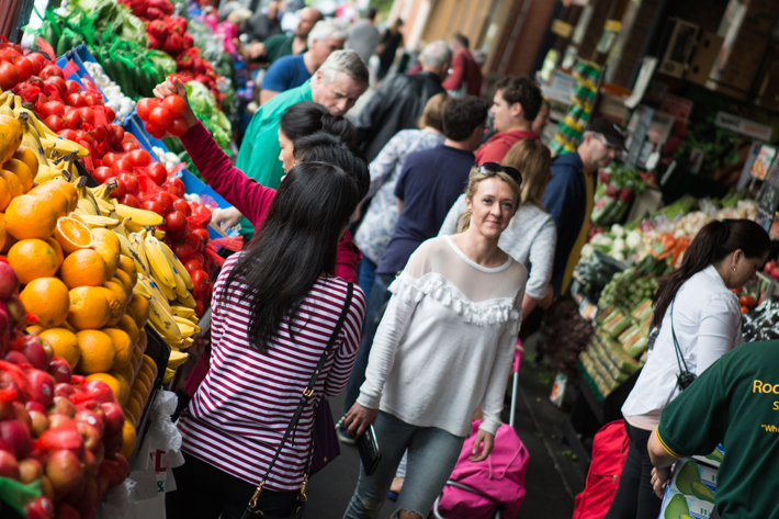woman walking past fruit and vegetable stall display