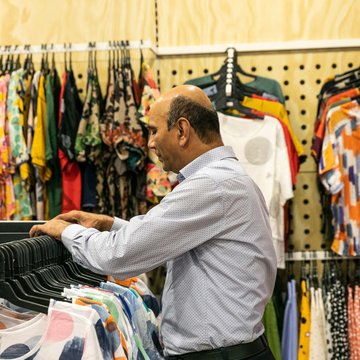 Person browsing colorful clothing in a store.