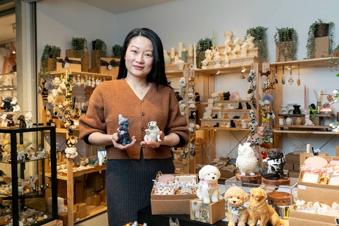 Person holding two figurines in a store filled with various animal figurines and ornaments.