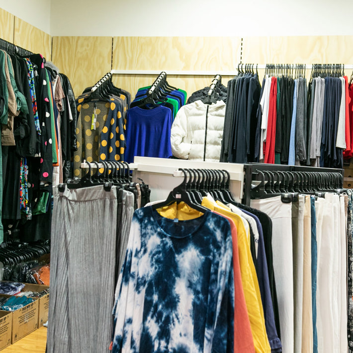 The image depicts a variety of clothing items displayed on hangers in a retail store