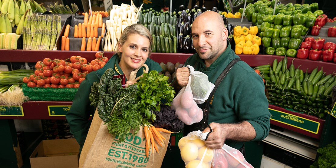 Roxy and Scott from Rod's Fruit and Vegetables holding bags of produce.