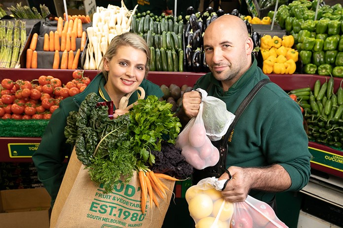 Roxy and Scott from Rod's Fruit and Vegetables holding bags of produce.